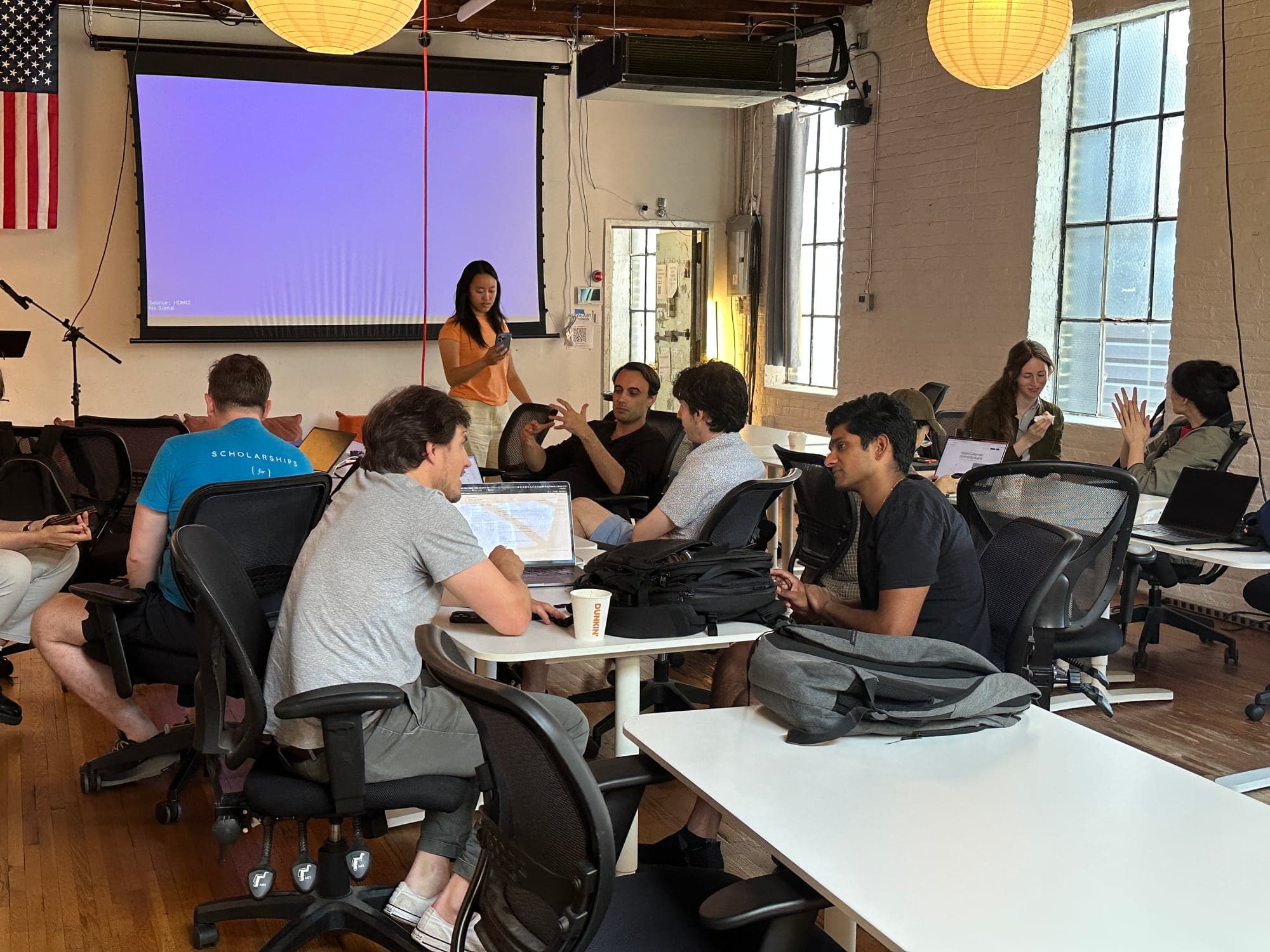Small groups of builders collaborating around tables at a HackerSquad event
